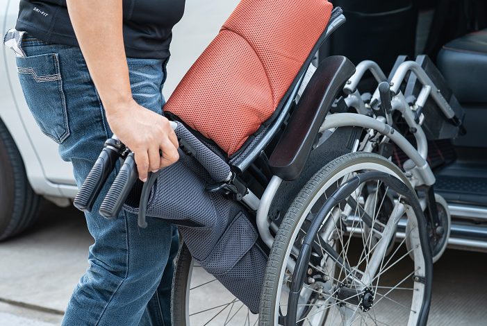 person lifting a manual wheelchair